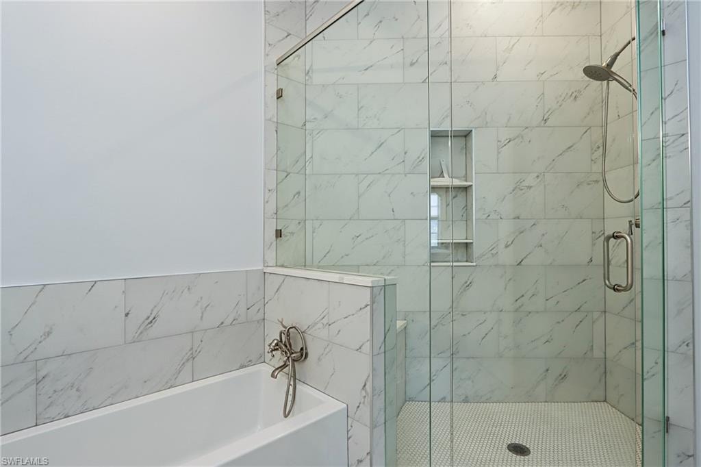 Full bath featuring a garden tub and a marble finish shower