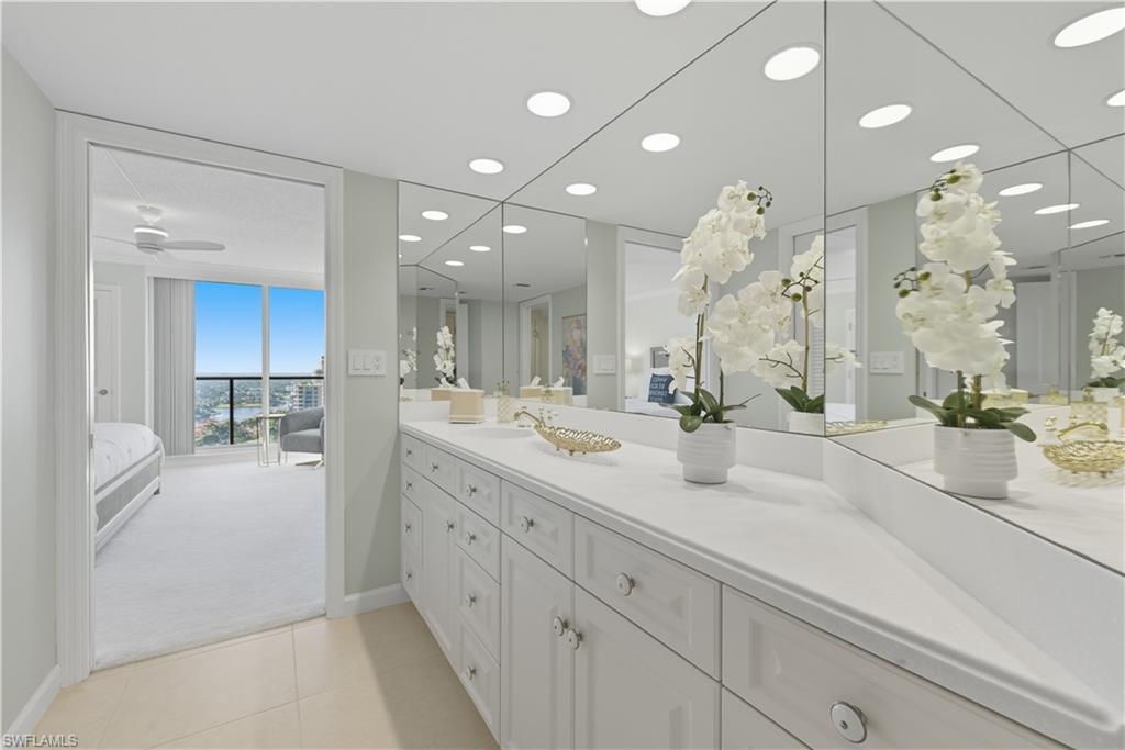 Vanity area featuring extensive wall-mounted mirrors and recessed lighting