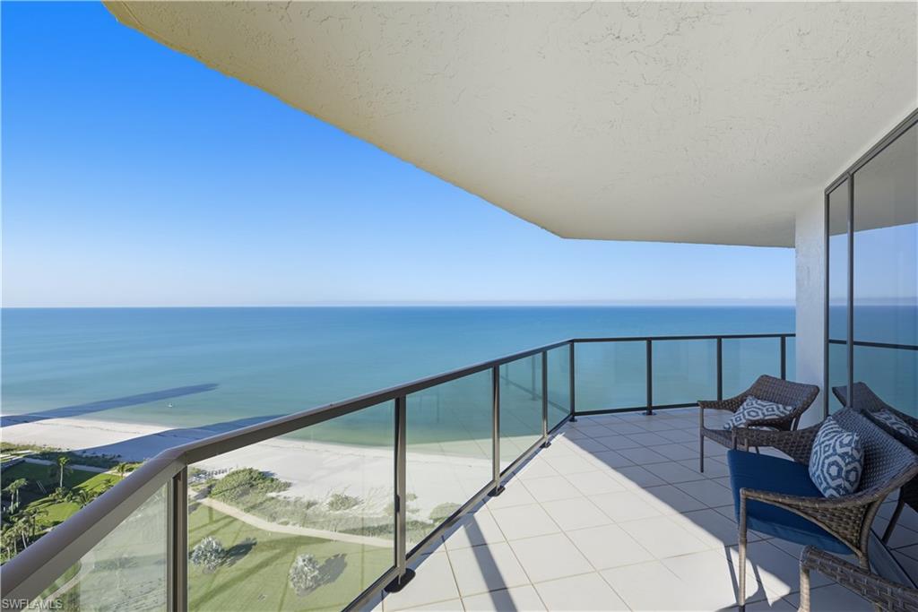 Expansive balcony featuring glass railings, a tile floor, and direct oceanfront exposure