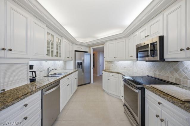 Galley kitchen featuring white cabinetry, stainless steel appliances, granite countertops, and a tiled backsplash