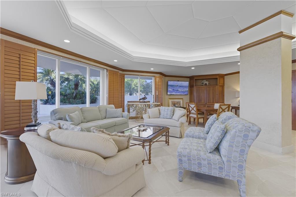 Spacious living area featuring large sliding glass doors, plantation shutters, and a coffered ceiling with recessed lighting