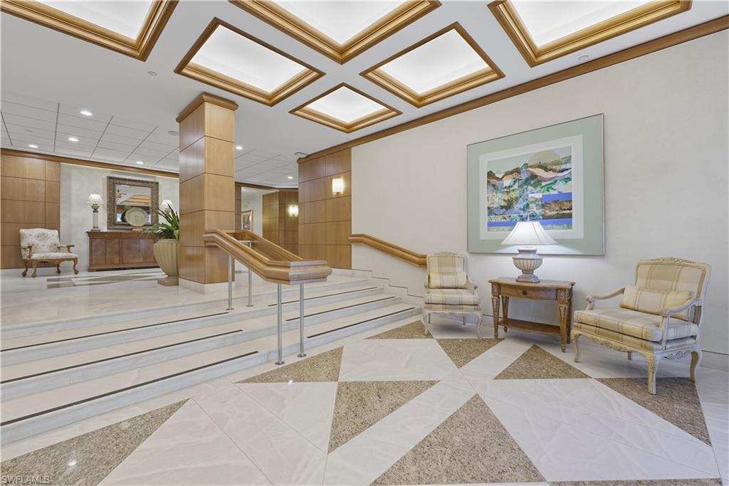 Grand entryway featuring a patterned tile floor, a staircase with wood handrails, wood paneling, and recessed ceiling lighting