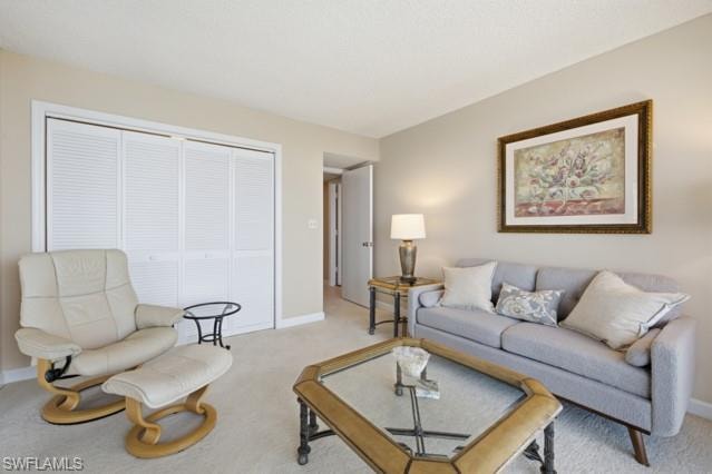 Living area featuring neutral wall tones, textured ceiling, light-toned carpeting, and white louvered bifold doors providing integrated storage