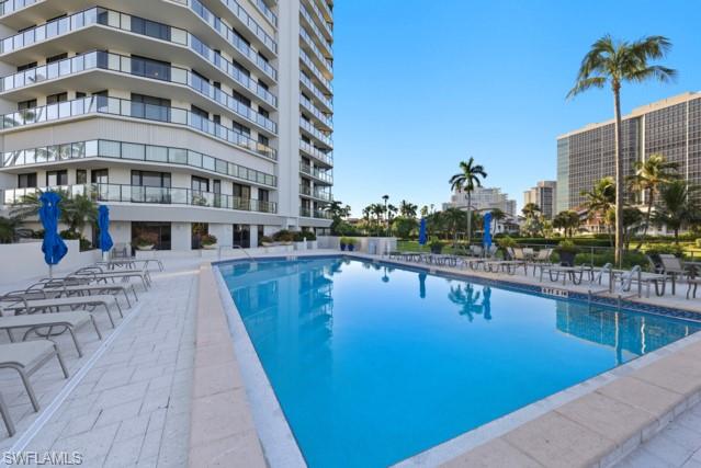 Outdoor swimming pool with a mosaic tile border, surrounded by a paved deck featuring a herringbone pattern