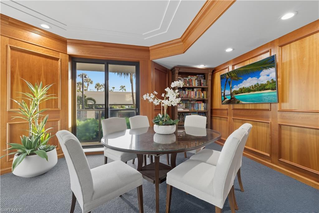 Recessed ceiling lighting illuminates a room featuring extensive wood paneling, a built-in bookshelf, and a sliding glass door
