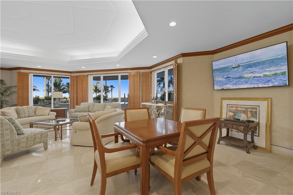 Bay window with plantation shutters and water views, featuring recessed lighting, tray ceiling, and tile flooring