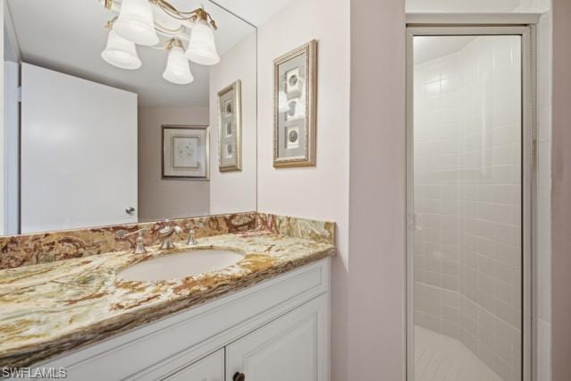 Bathroom featuring a vanity with a colorful stone countertop, an undermount sink, and a mirrored wall
