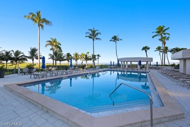 Rectangular swimming pool featuring a tiled perimeter and integrated steps with a metal handrail