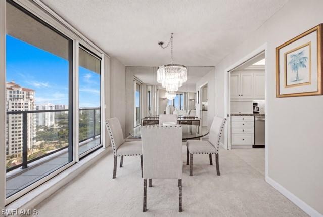 Dining area featuring a chandelier, mirrored wall, and sliding glass doors opening to a balcony