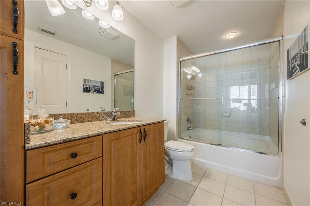 Full bathroom featuring tile patterned flooring, vanity, shower / bath combination with glass door, and toilet