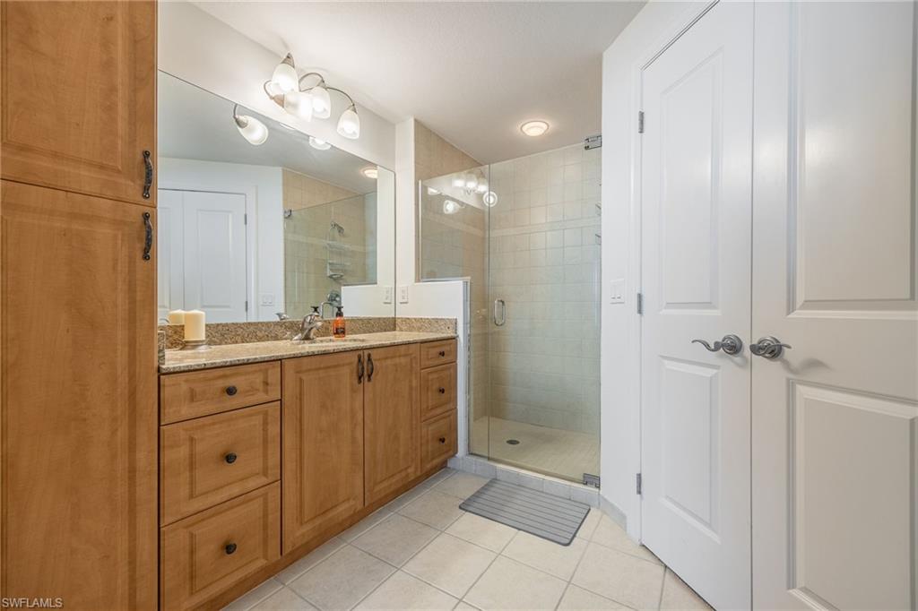 Bathroom with tile patterned flooring, vanity, and a shower with door
