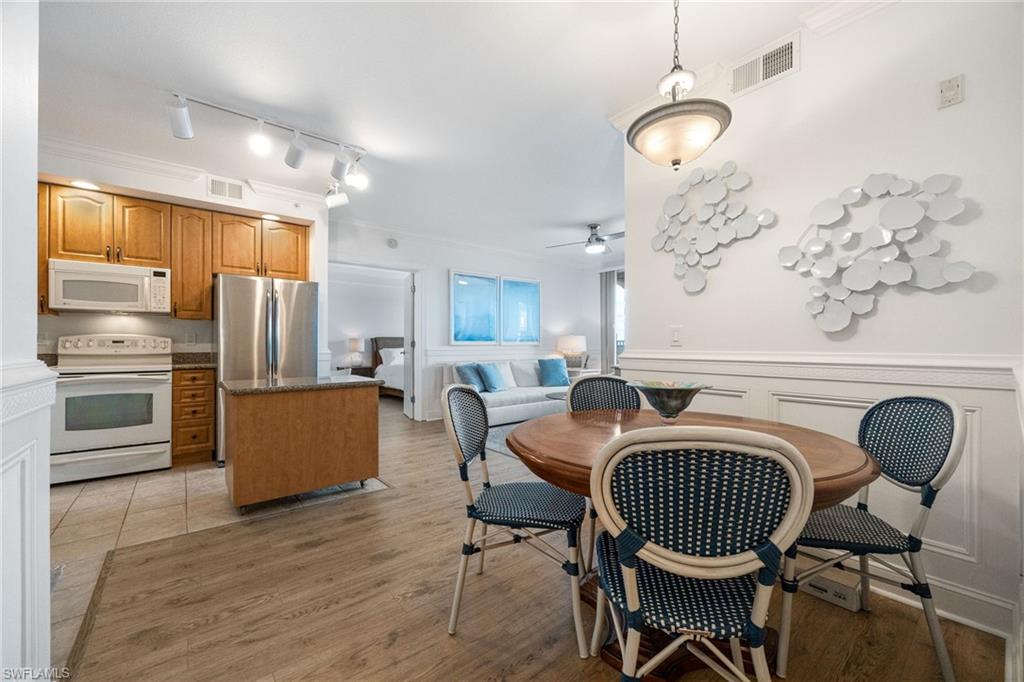 Dining room with ornamental molding, rail lighting, ceiling fan, and light hardwood / wood-style flooring