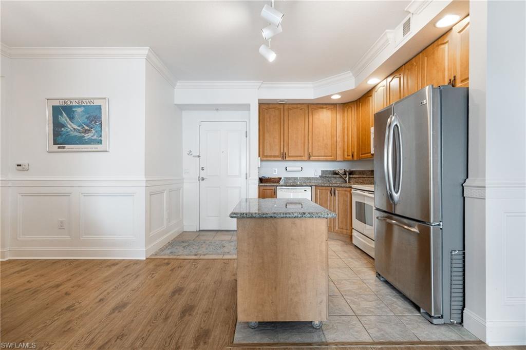 Kitchen featuring rail lighting, light hardwood / wood-style flooring, ornamental molding, a kitchen island, and white appliances
