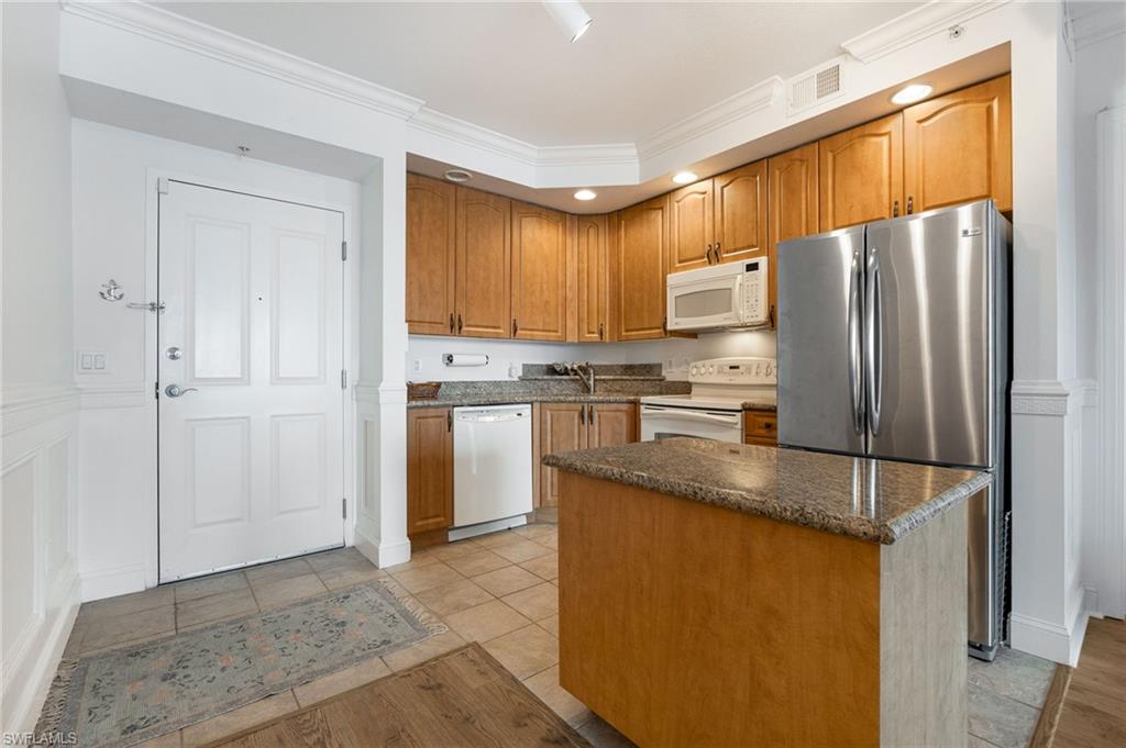 Kitchen featuring crown molding, white appliances, a kitchen island, and light tile patterned floors