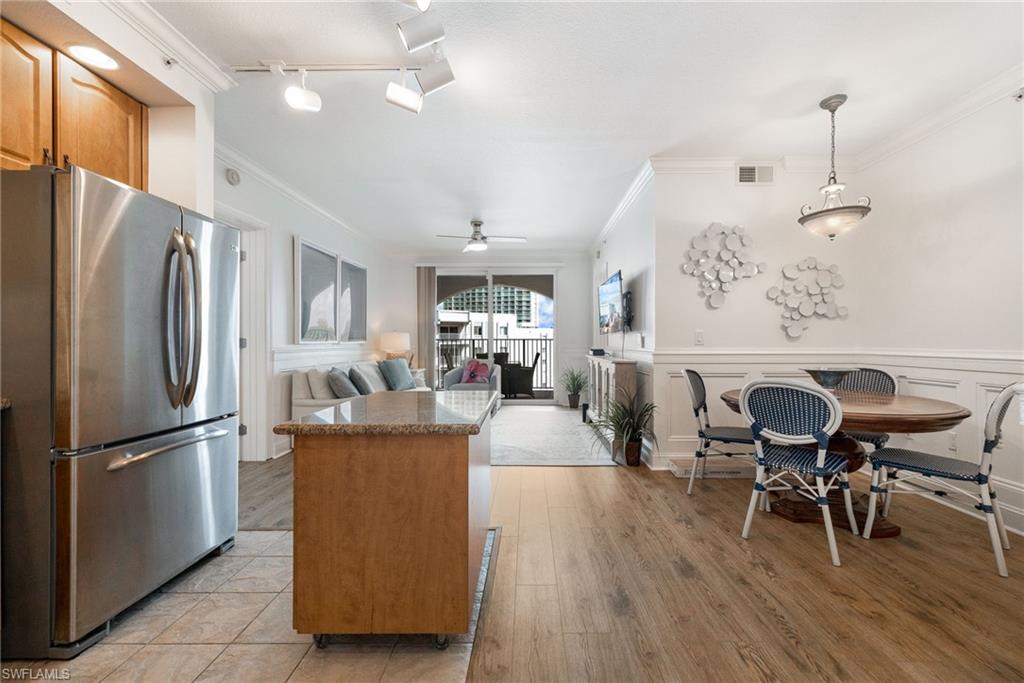 Kitchen featuring hanging light fixtures, track lighting, ornamental molding, stainless steel fridge, and light hardwood / wood-style floors