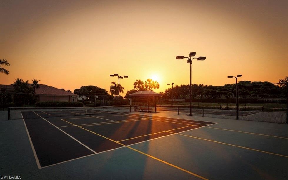 Outdoor tennis courts featuring hard surfaces, perimeter fencing, and integrated lighting fixtures