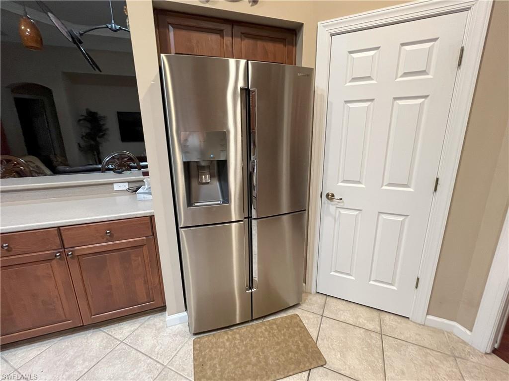 Stainless steel four-door refrigerator with ice and water dispenser, complemented by light-toned square floor tiling