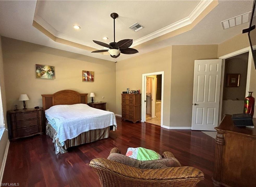 Spacious room featuring rich wood-finish flooring, a tray ceiling with recessed lighting, and a ceiling fan