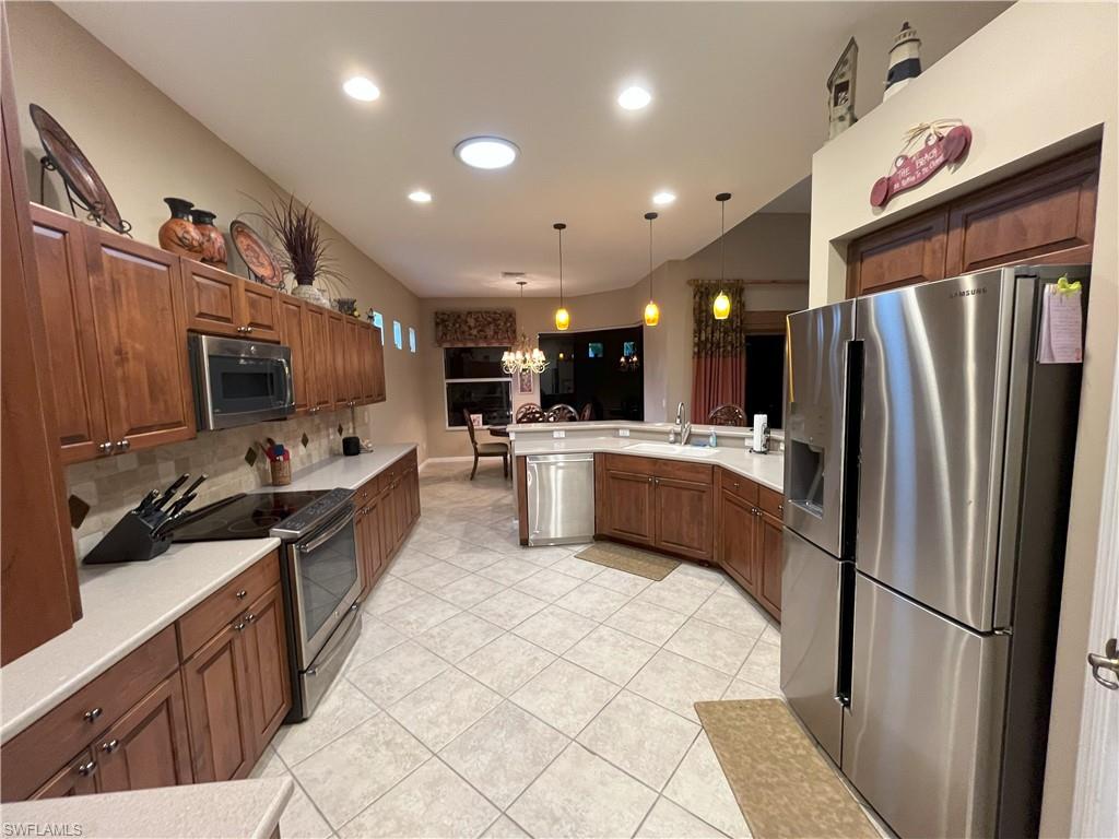 Spacious kitchen featuring warm wood cabinetry, light-toned countertops, and stainless steel appliances