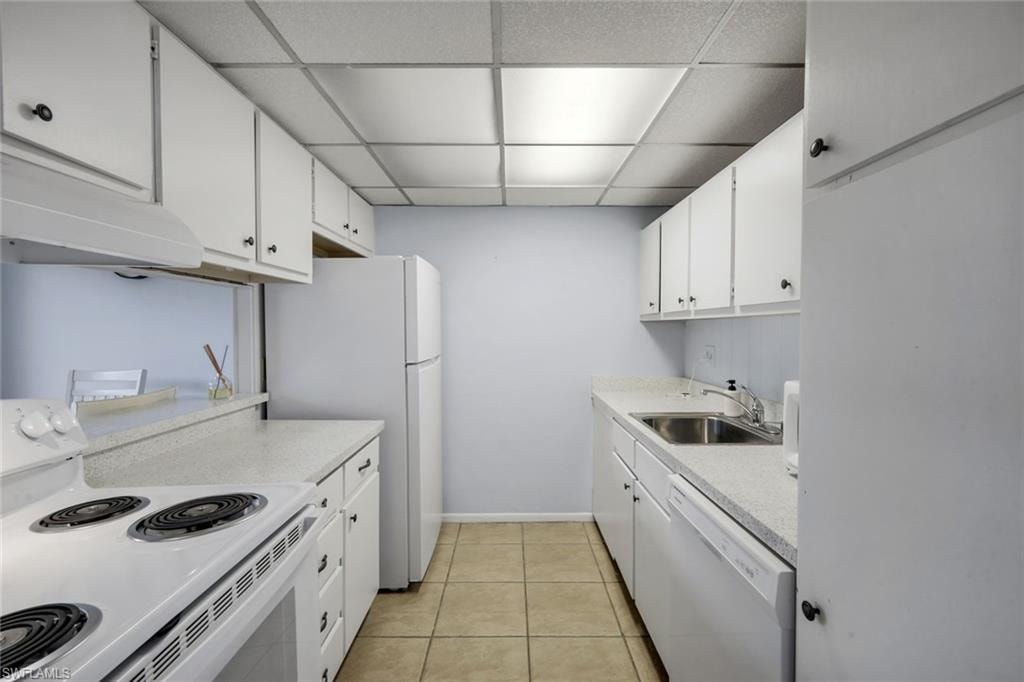Galley kitchen featuring white cabinetry, light-toned countertops, and tile flooring