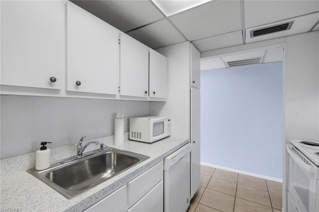 Kitchen featuring white cabinetry, speckled countertops, and a double-basin stainless steel sink with a chrome faucet