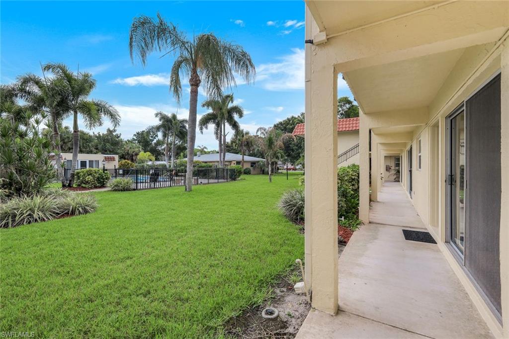 Expansive green space featuring palm trees, a fenced in-ground pool, and established landscaping
