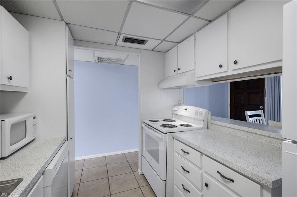 Galley kitchen featuring white cabinetry, light-toned countertops, a white electric range, and tile flooring