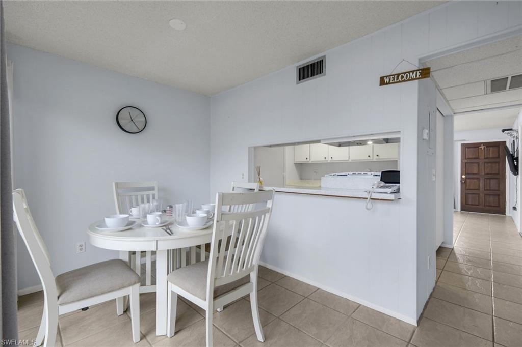 Dining area featuring tile flooring, white walls, and a pass-through opening to the kitchen