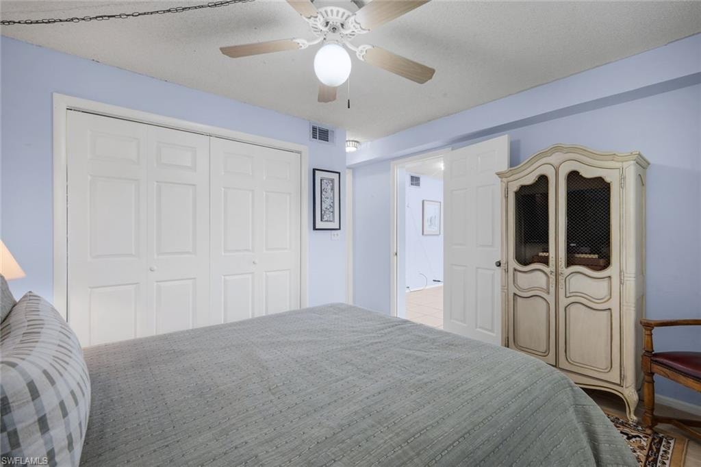 Bedroom featuring a ceiling fan with integrated lighting, white bi-fold closet doors, and light blue wall color