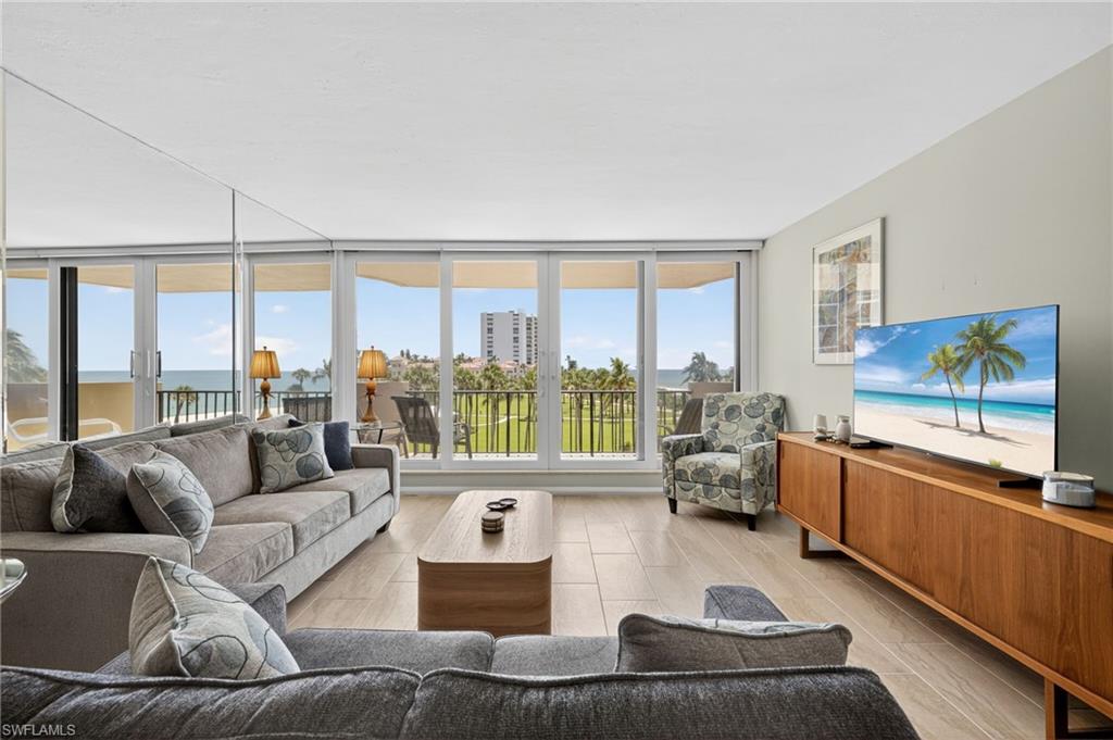 Living area with light wood-style flooring, a water view, and floor to ceiling windows