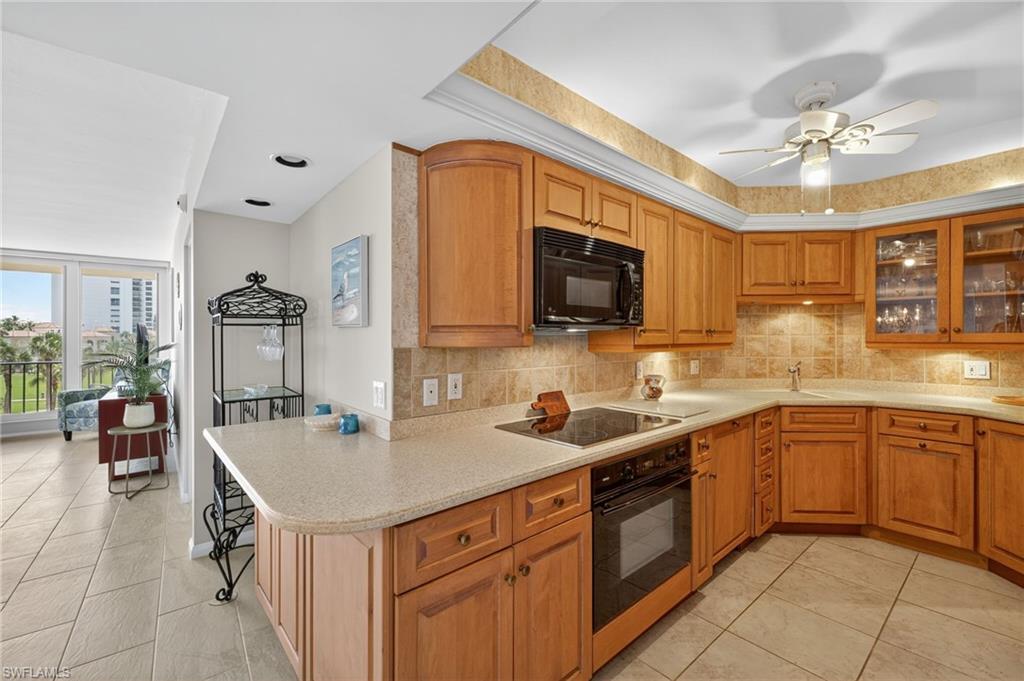 Kitchen with backsplash, black appliances, light tile patterned floors, and light countertops