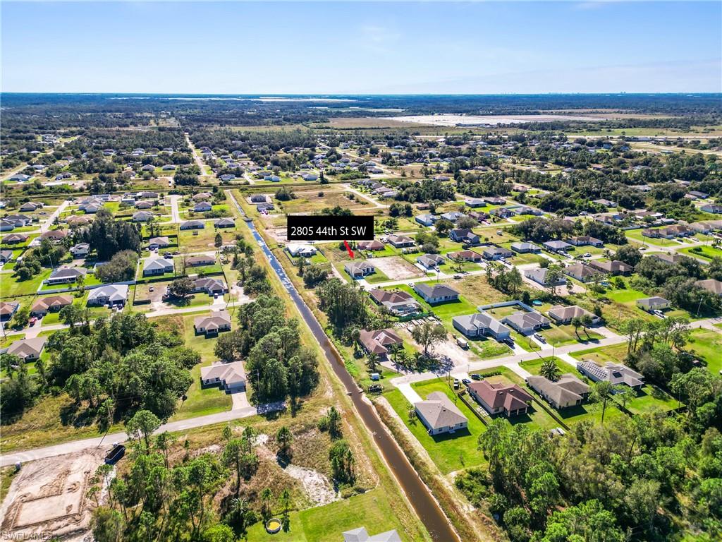 Residential neighborhood featuring a canal, paved roads, and scattered mature trees