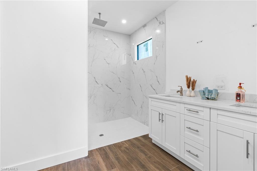 Modern bathroom featuring a spacious walk-in shower with full-height marble-patterned tile, a square rain shower head, and a transom window