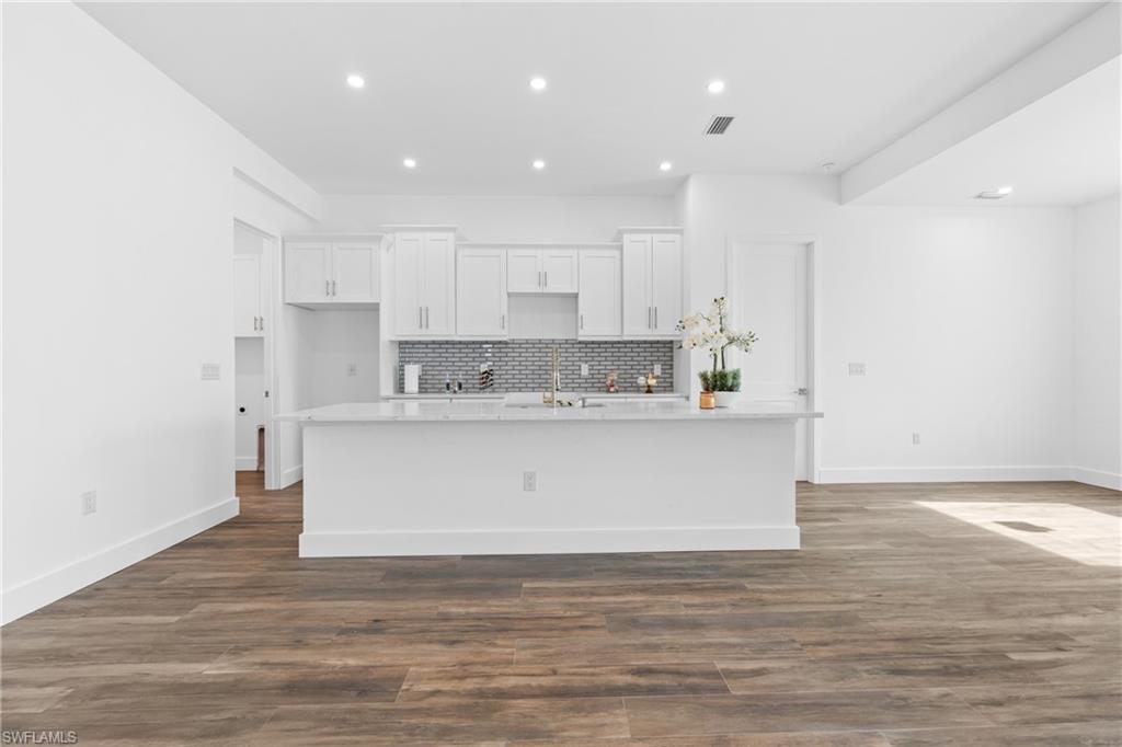 Kitchen featuring a white island with a light-toned countertop, white cabinetry, and a gray subway tile backsplash