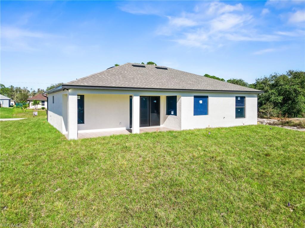 Rear exterior featuring a stucco finish and a shingled roof
