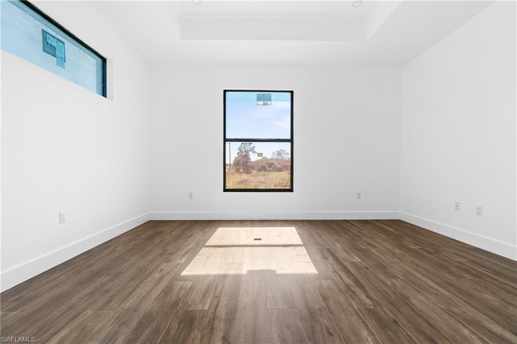 Spacious interior featuring wood-finish flooring, white walls, and a tray ceiling