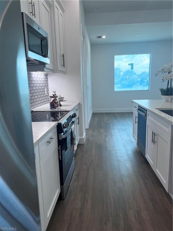 Kitchen featuring white cabinetry with silver hardware, stone countertops, and a subway tile backsplash