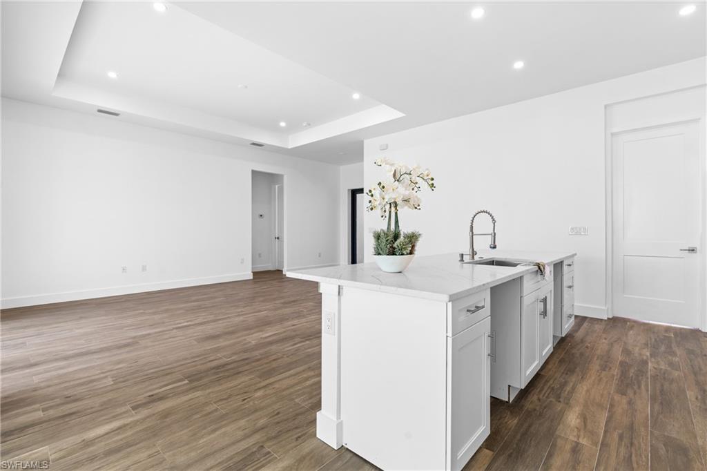 Kitchen island featuring a single-basin sink with a gooseneck faucet, white cabinetry, and a light-toned countertop