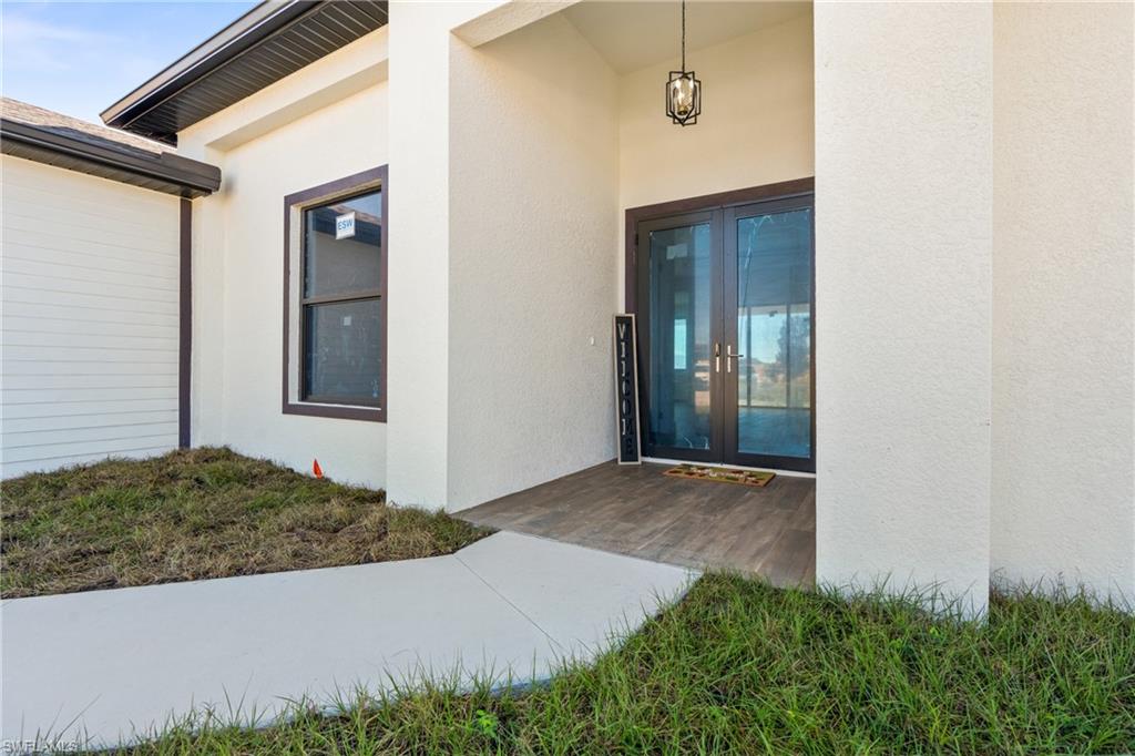 Entryway featuring double glass doors, a wood-finish porch, and a contemporary hanging light fixture
