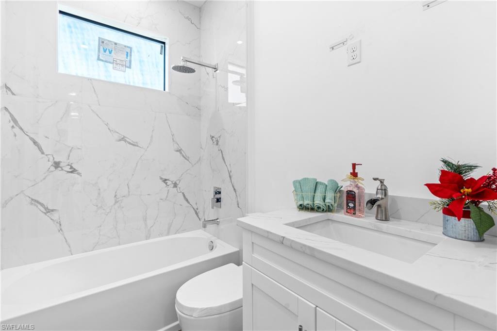Bathroom featuring a white vanity with an integrated sink, polished chrome faucet, and a large soaking tub