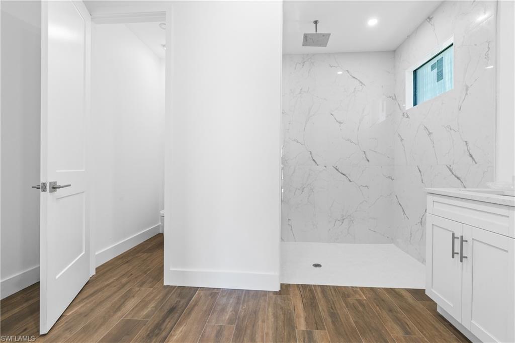 Spacious shower enclosure with marble-look wall tiling and a rainfall showerhead