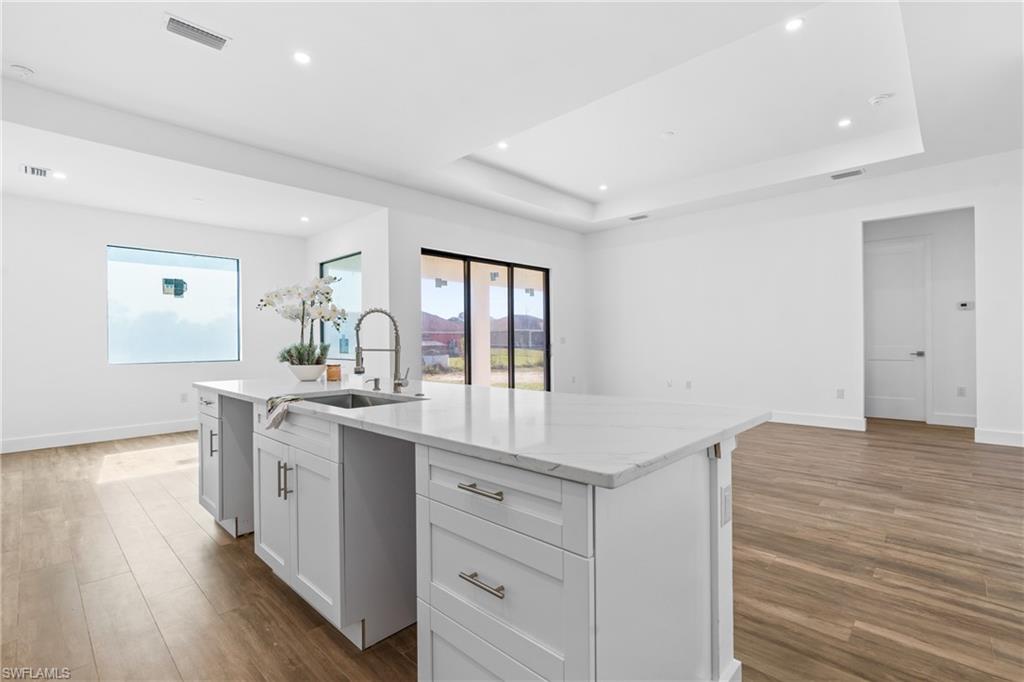 Spacious kitchen island featuring a stainless steel sink, contemporary faucet, and light-toned countertop
