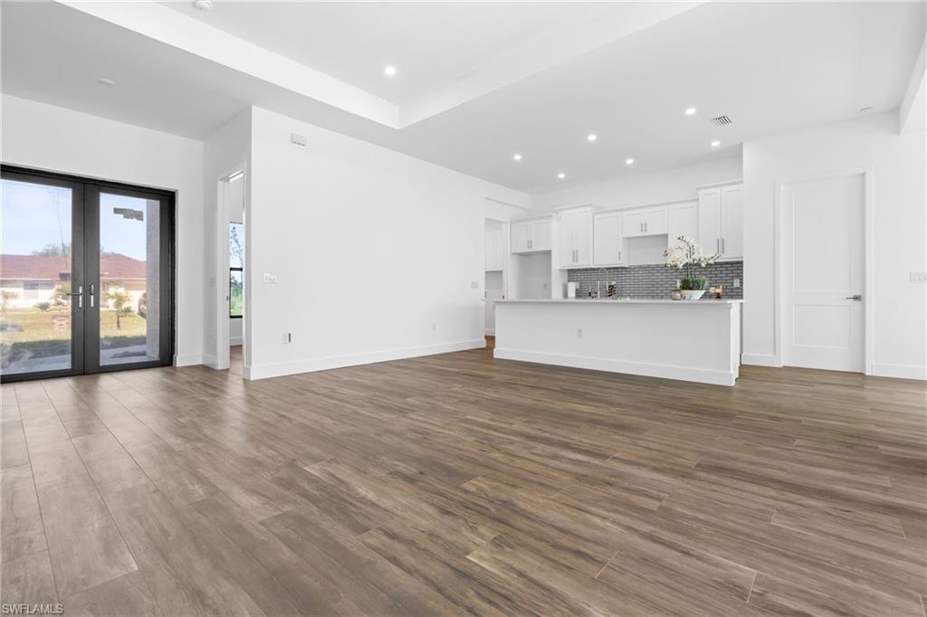 Open-concept living space featuring wood-finish flooring, recessed lighting, and a tray ceiling