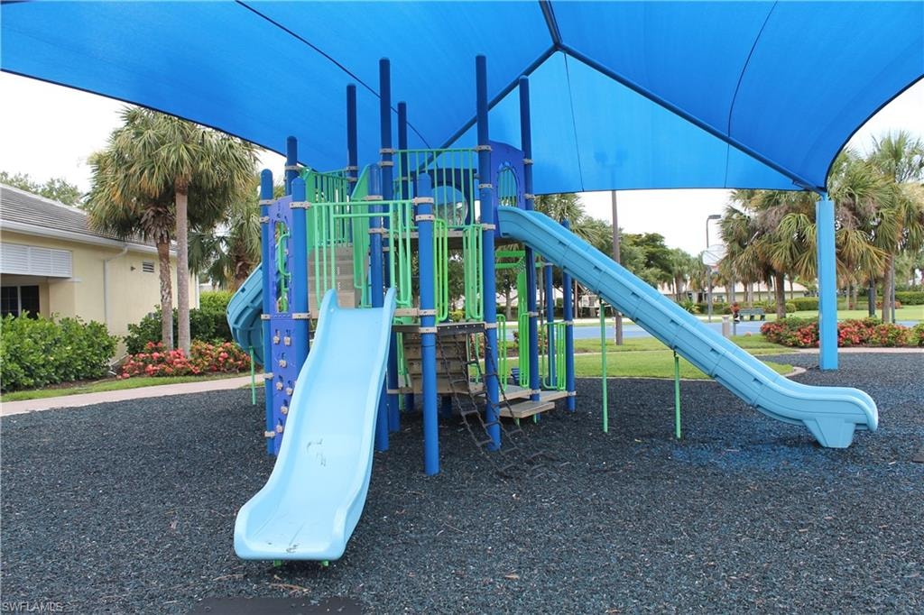 Playground structure featuring blue and green components, multiple slides, and a blue shade canopy