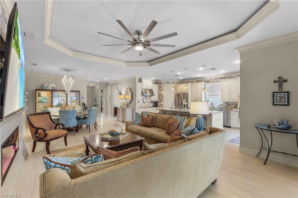 Open-concept living area with wood-finish flooring, tray ceiling, and a built-in fireplace