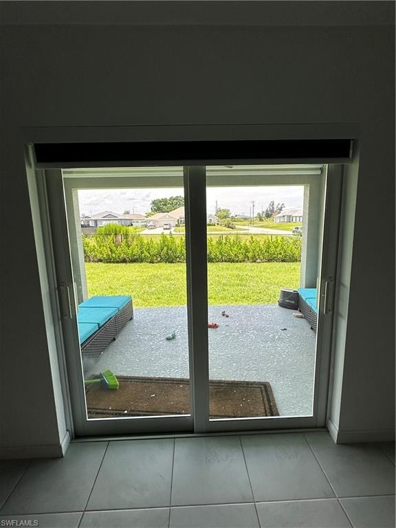 Sliding glass doors opening to a concrete patio and expansive green lawn, featuring an adjacent brush line and distant residential structures
