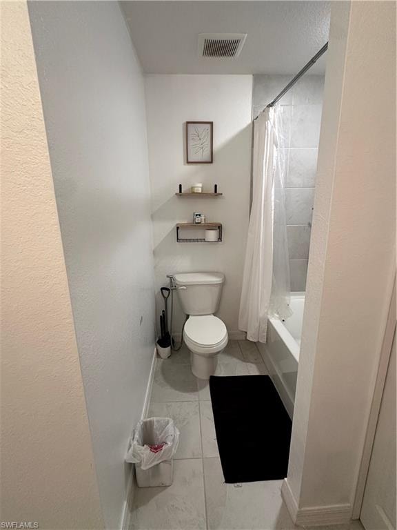 Full bathroom featuring a white porcelain toilet, tiled flooring, built-in bathtub with tiled surround, and ceiling-mounted exhaust fan