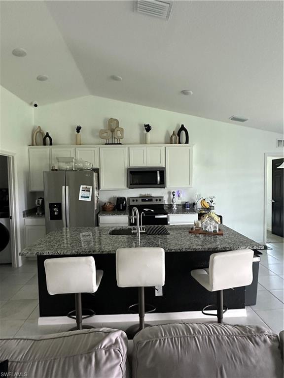 Kitchen featuring a vaulted ceiling with recessed lighting, granite countertops, white cabinetry, and stainless steel appliances