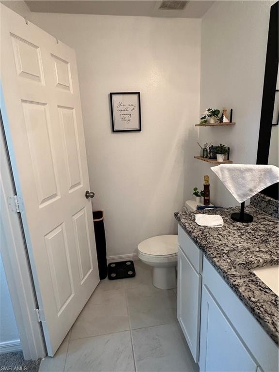 Bathroom featuring a white paneled door, light-toned tile flooring, and a vanity with a patterned countertop