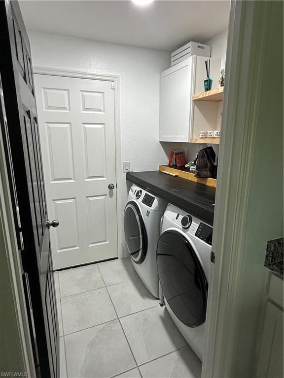 Dedicated laundry area featuring a dark wood-finish countertop, white cabinetry with integrated shelving, and light-toned tile flooring